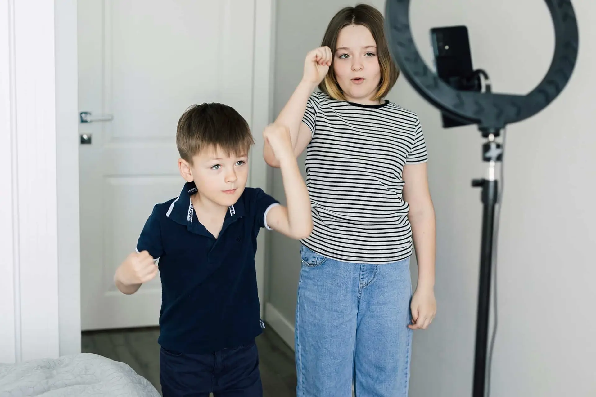 Un ragazzo e una ragazza adolescente che utilizzano il telefono cellulare realizzano videoclip danzanti da condividere sull'applicazione tiktok