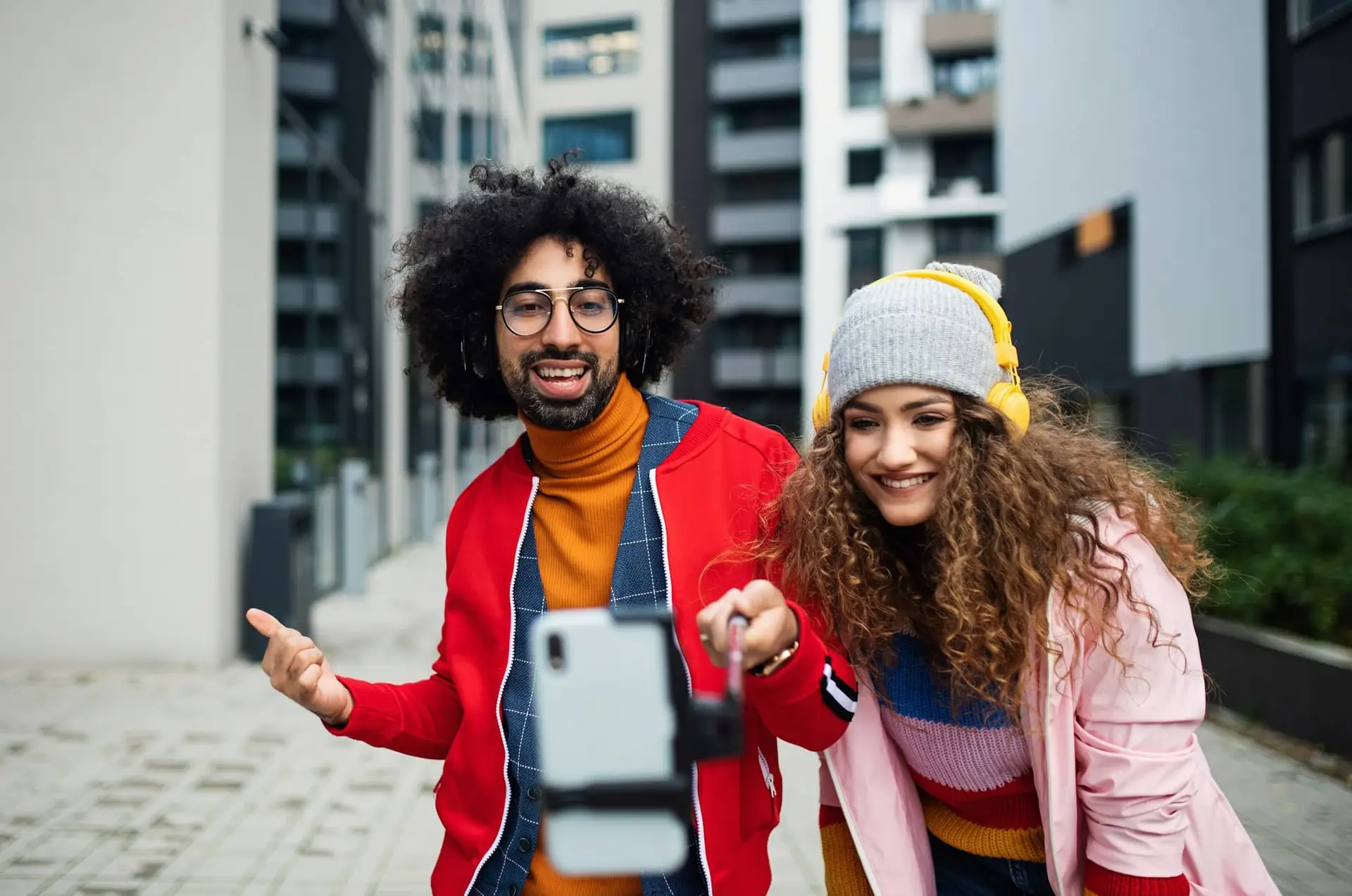 Giovane coppia con smartphone che realizza video all'aperto sulla strada, concetto tik tok.